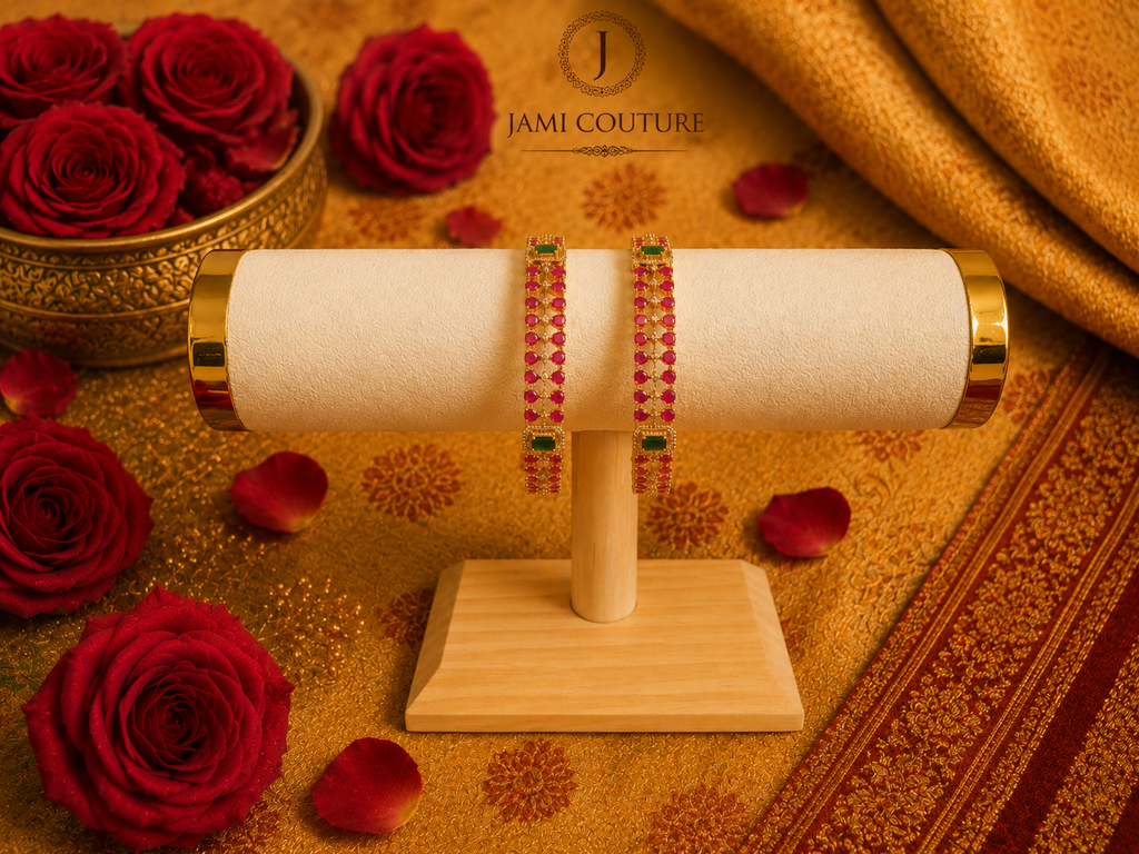 Zirconia ruby and emerald studded bangles displayed on a bangle bar among roses