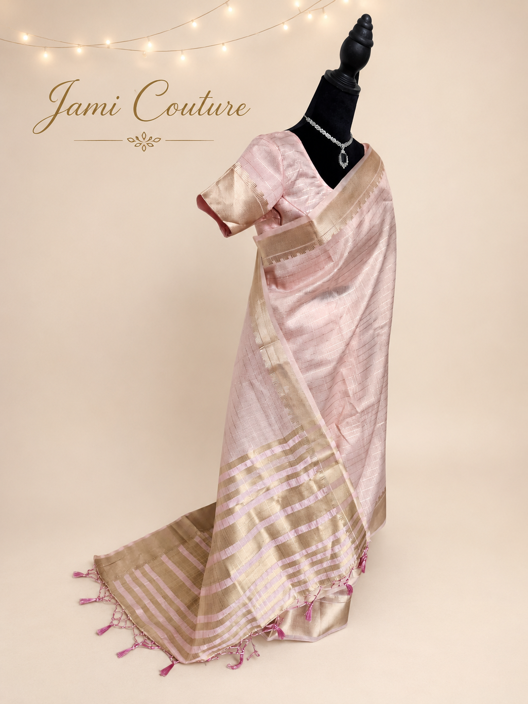 Side view of the baby pink tissue organza saree showing the gold-striped pallu with pink tassels and matching blouse