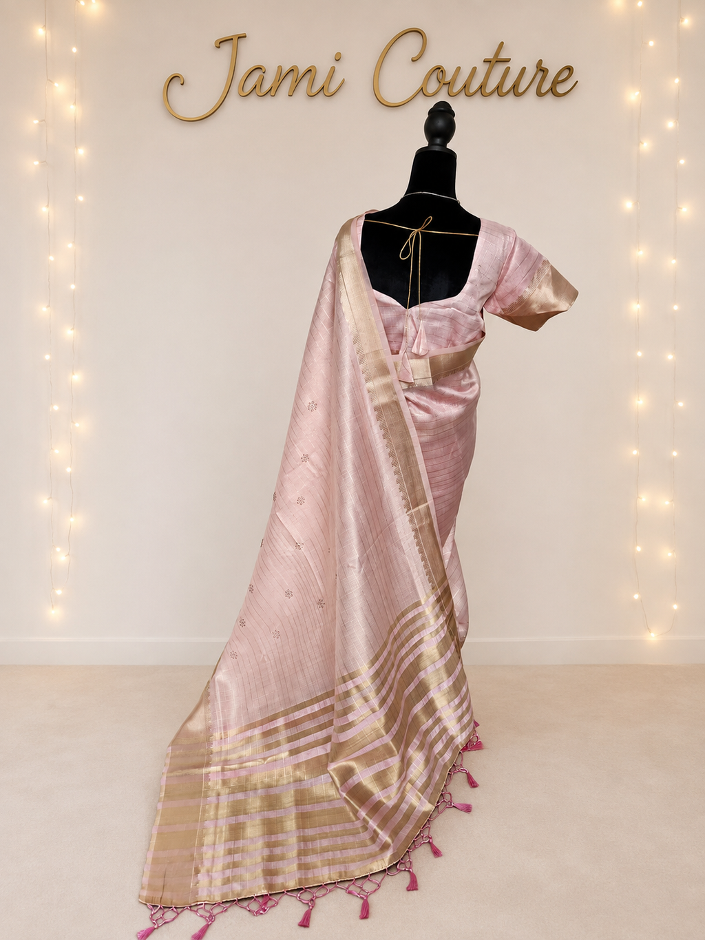 Full-length back view of the baby pink tissue organza saree with gold-striped pallu and pink tassels trailing to the floor