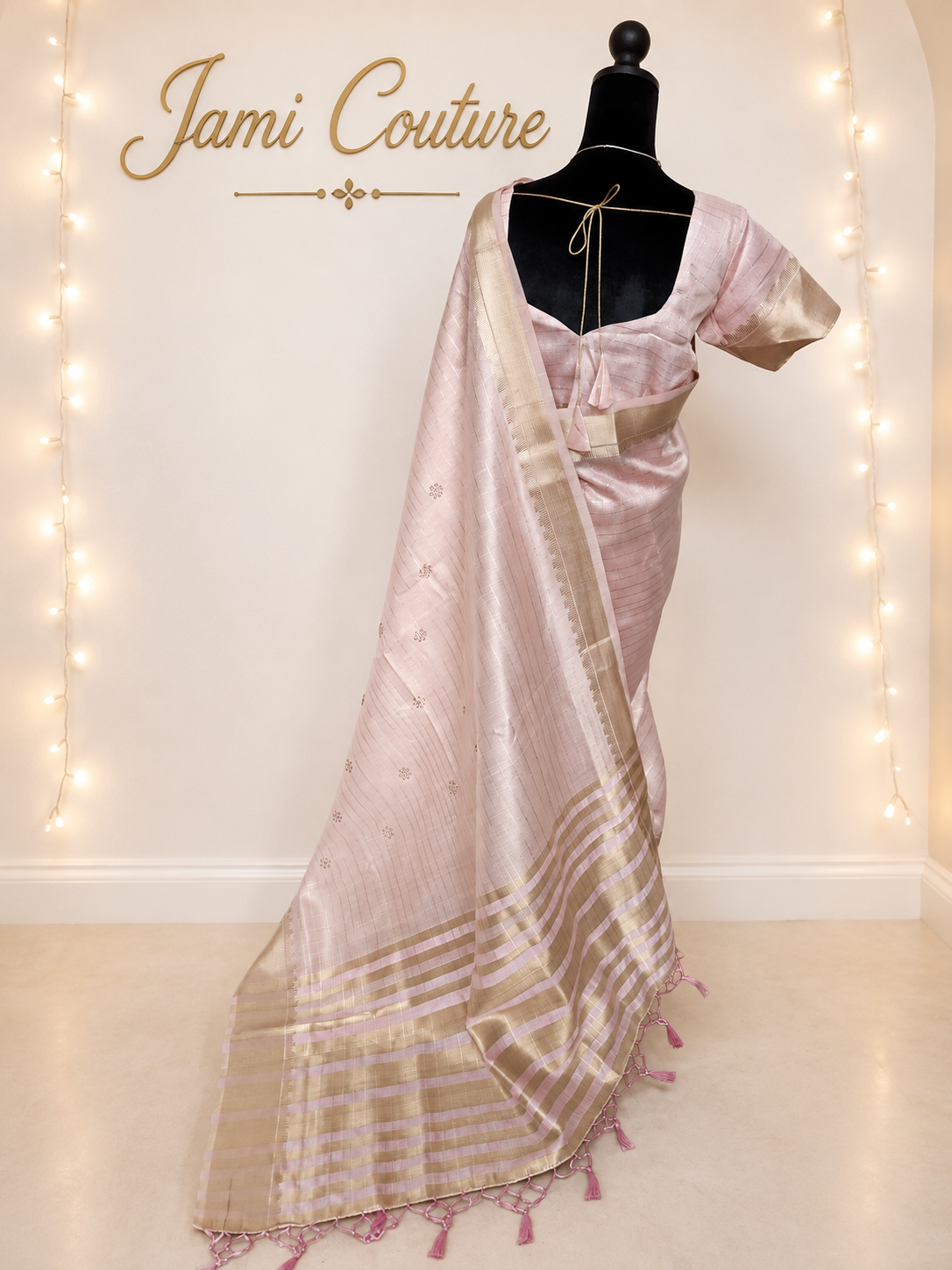Back view of the baby pink tissue organza saree with the pallu over the shoulder, scattered zari buttis and pink tassels
