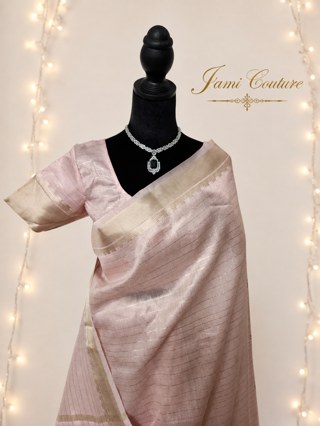 Close-up of the baby pink saree front showing fine gold zari checks and the matching stitched blouse with zari-bordered sleeves