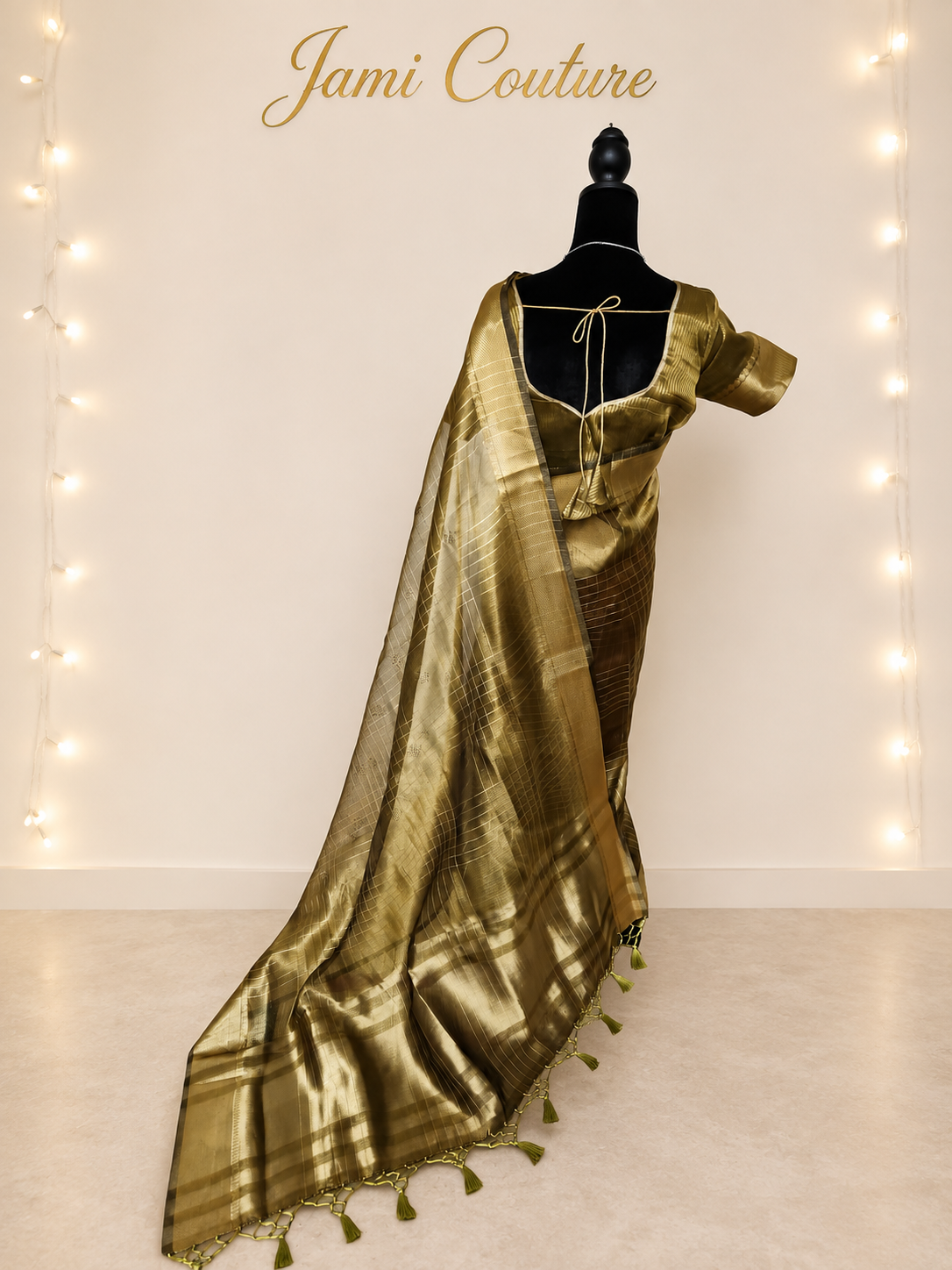Side-back view of the olive-gold tissue organza saree showing the sheer pallu and tassels