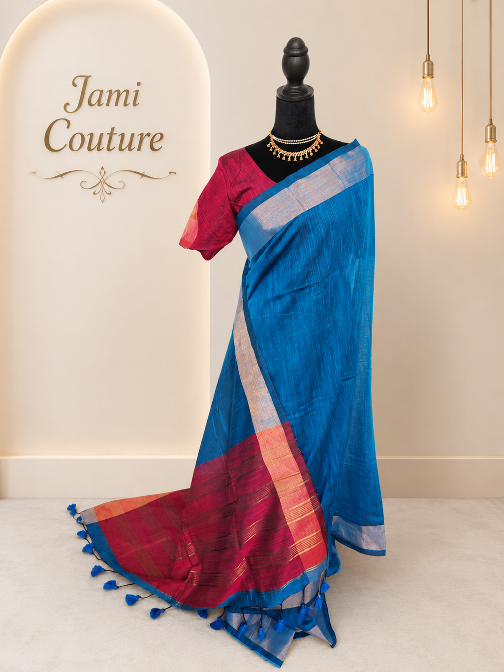 Blue khadi cotton saree with contrast pink pallu and tassels, pink stitched blouse, draped on a mannequin, front view