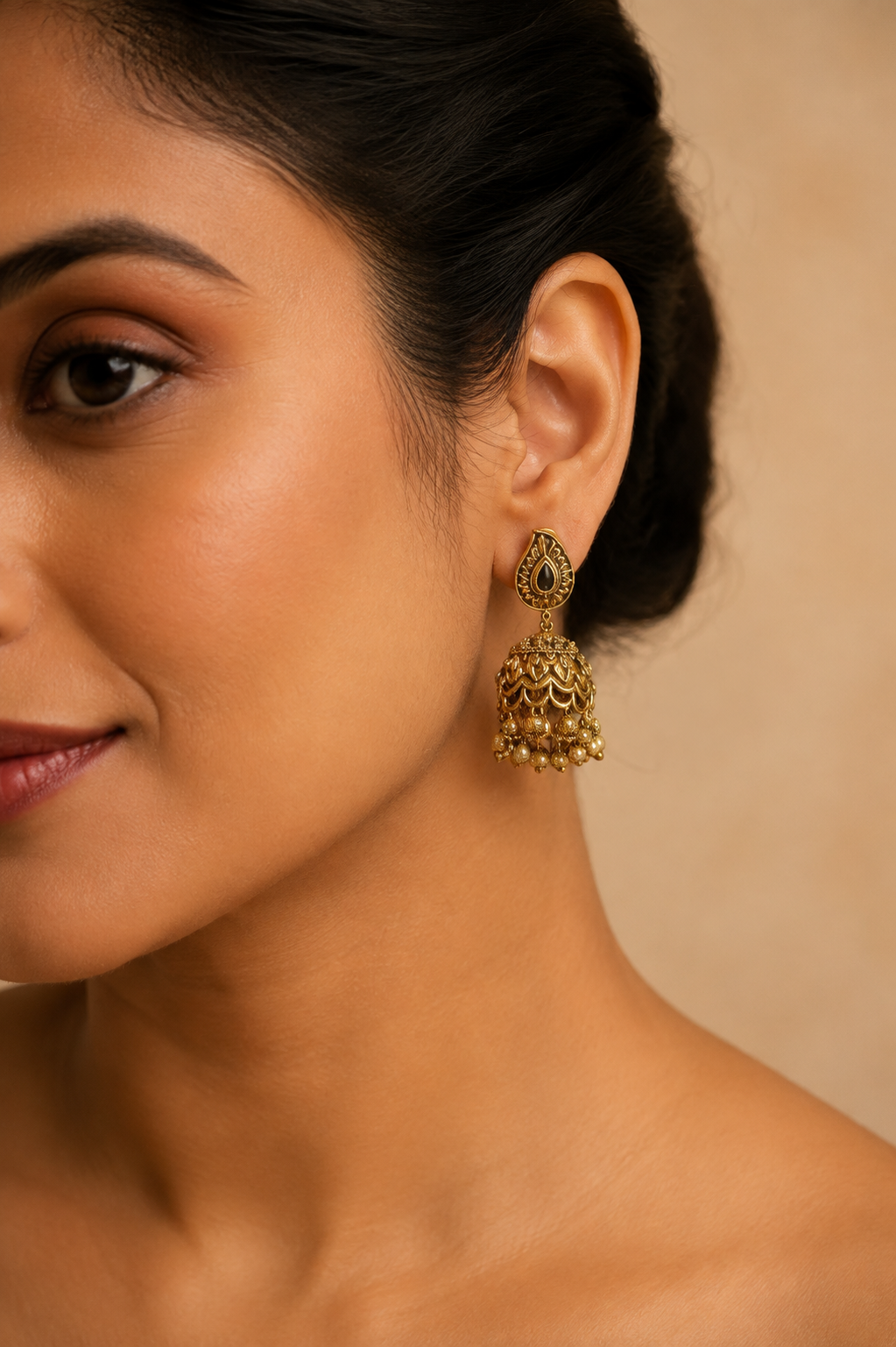 Model wearing an antique gold paisley jhumka earring, profile view