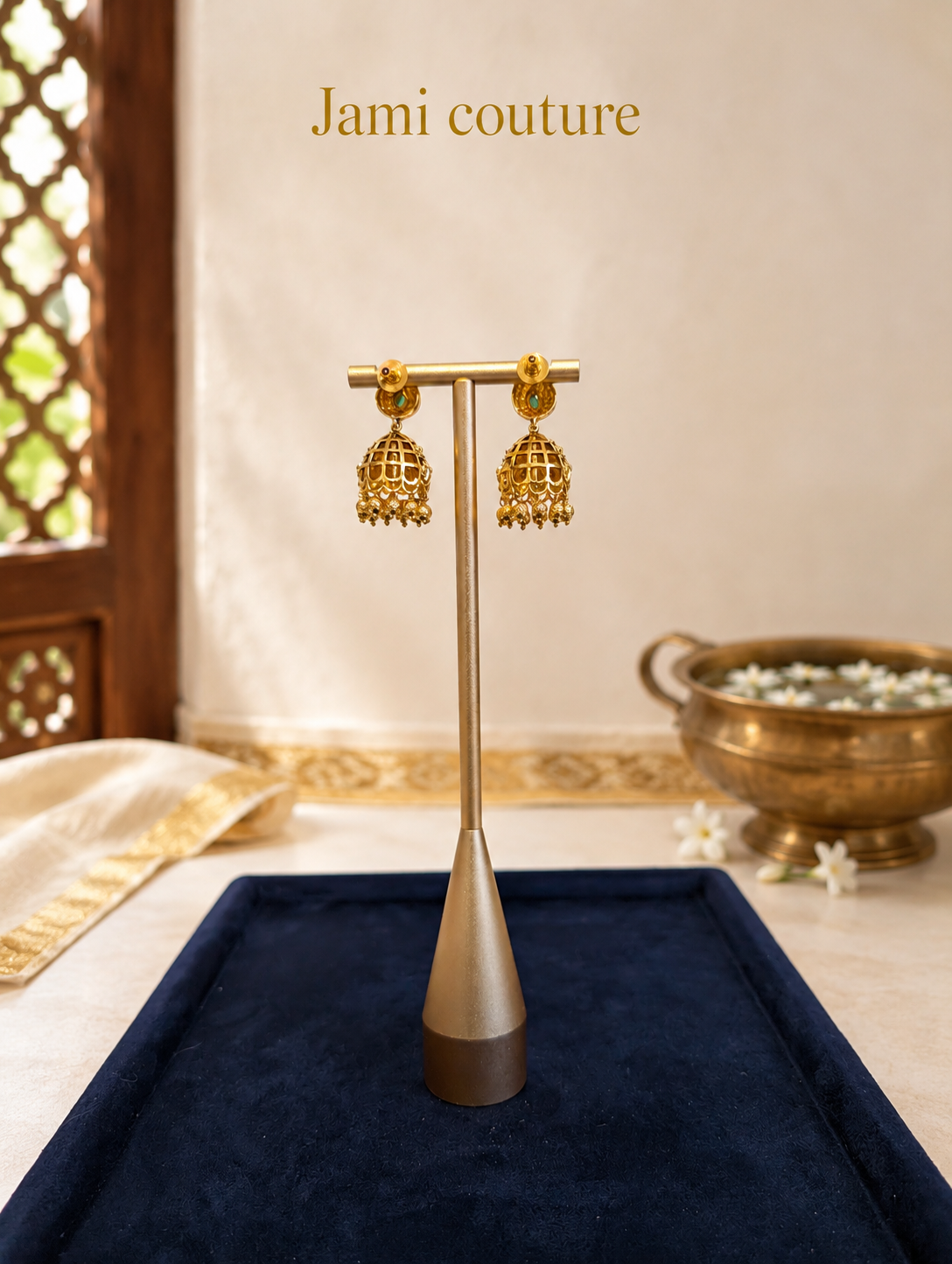 Close view of the paisley jhumka earrings on a stand over navy velvet