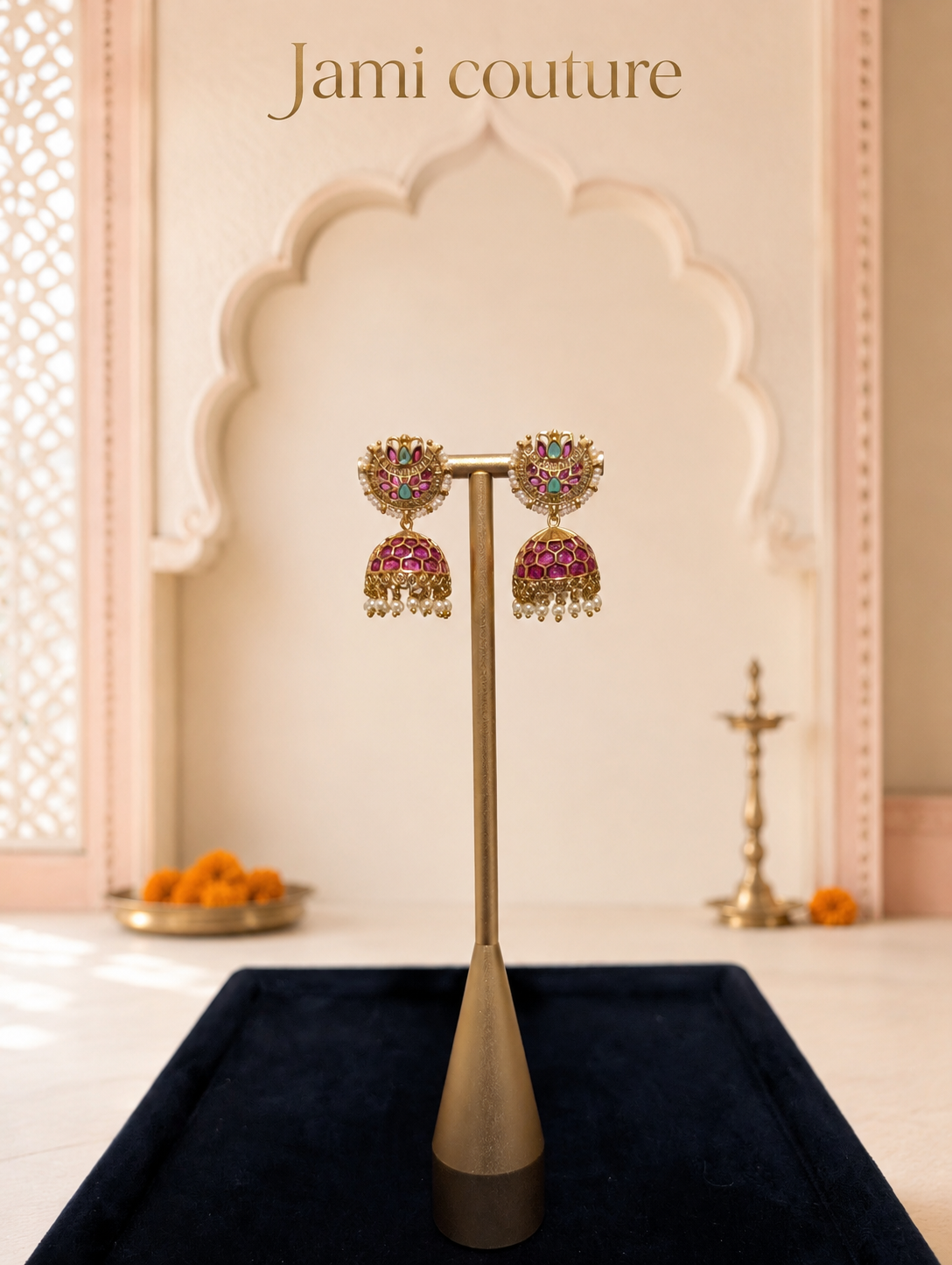 Ruby, emerald and white kundan jhumka earrings on a stand over navy velvet