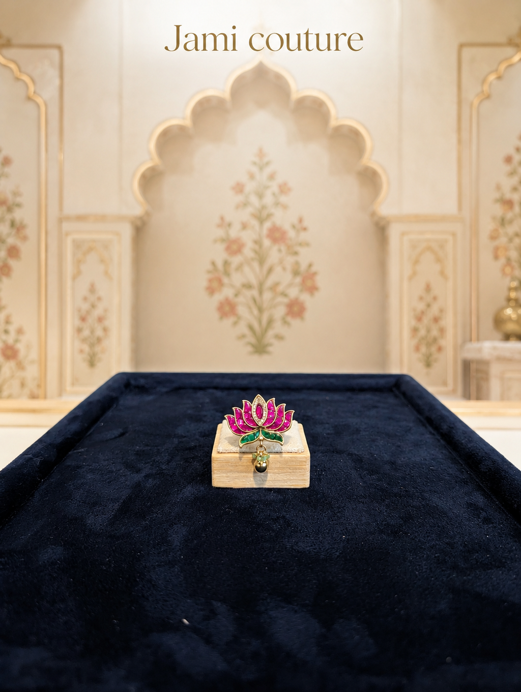 Ruby and emerald lotus jadau ring on a block over navy velvet in an arched setting