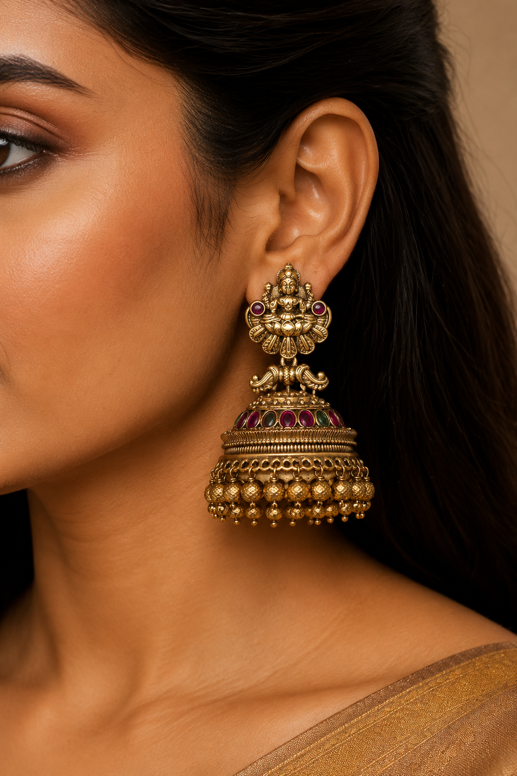 Model wearing a large antique gold Lakshmi temple jhumka earring, profile view