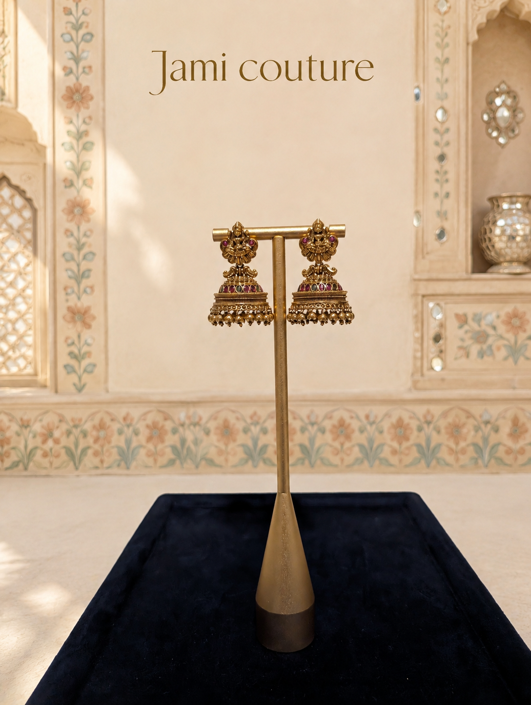 Antique gold Lakshmi temple jhumka earrings on a gold stand over a navy tray