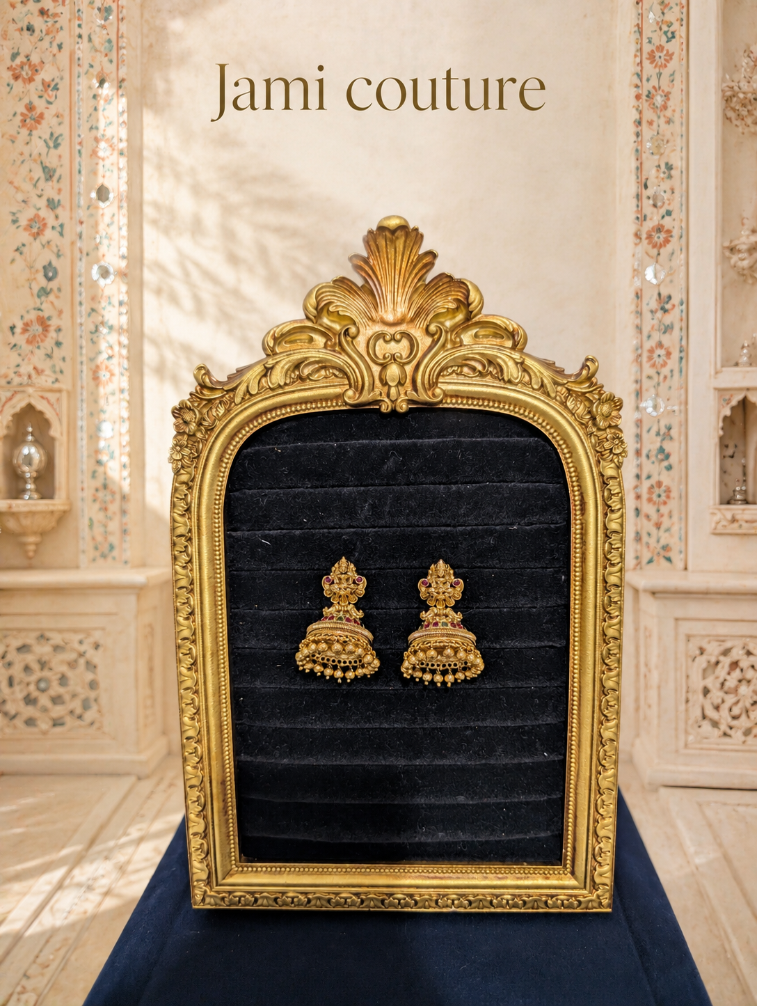 Antique gold Lakshmi temple jhumka earrings displayed on black velvet in a gold frame