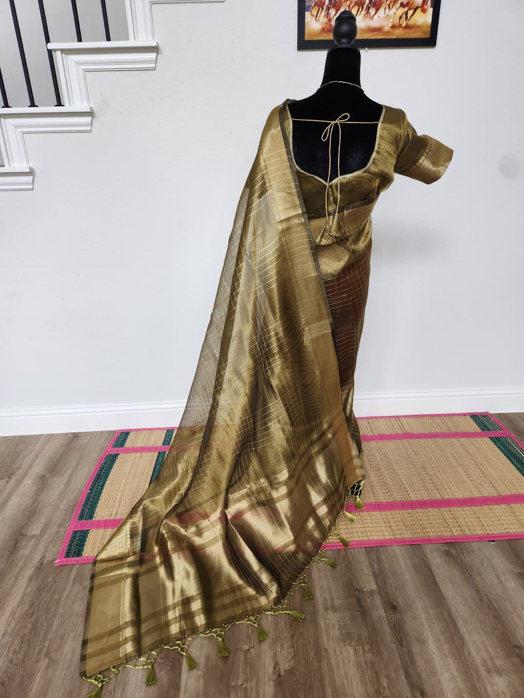 Natural-light side-back view of the olive-gold organza saree and tasseled pallu