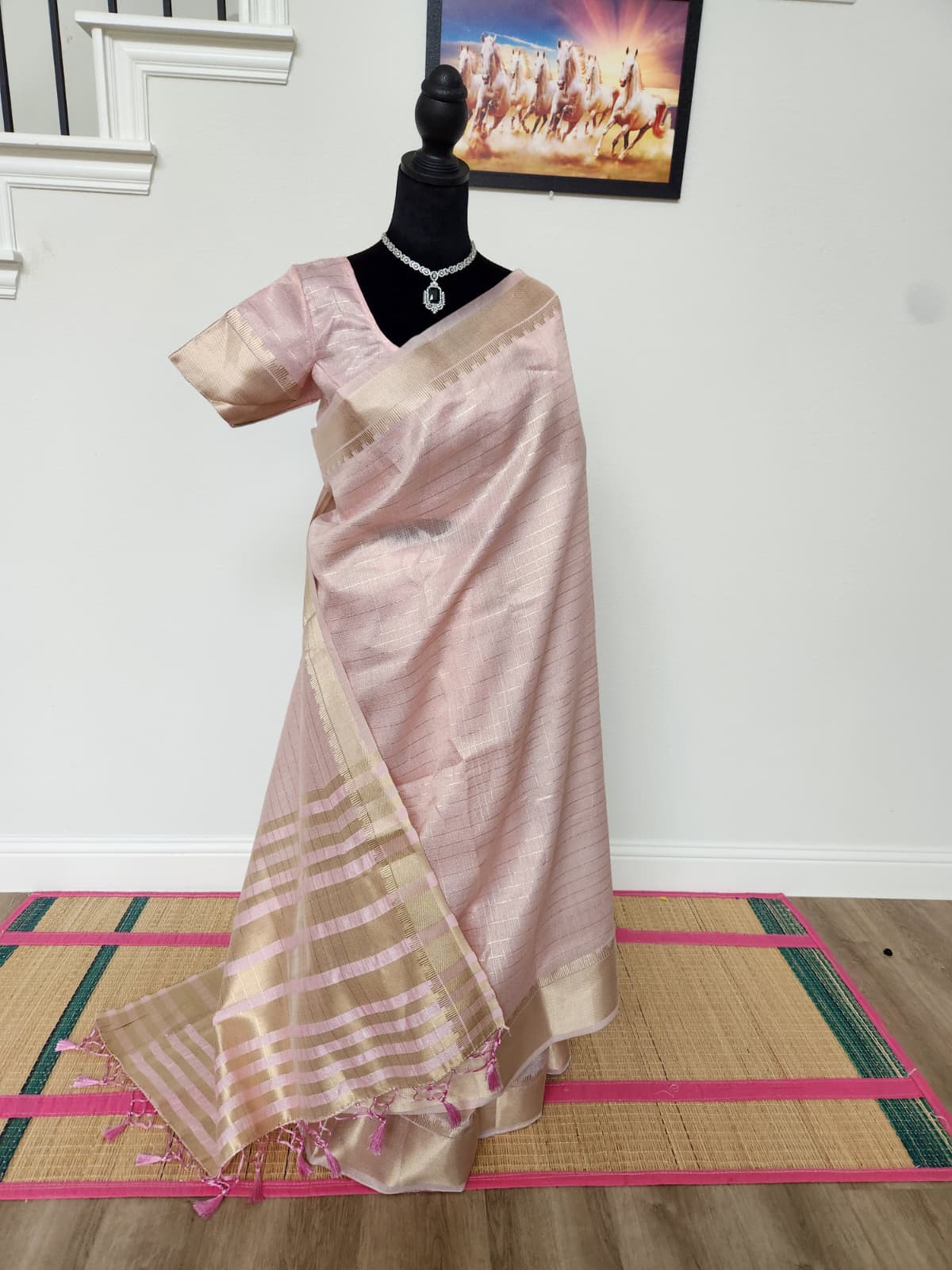 Natural-light front view of the baby pink saree with gold zari checks on the body and the pallu falling to the floor