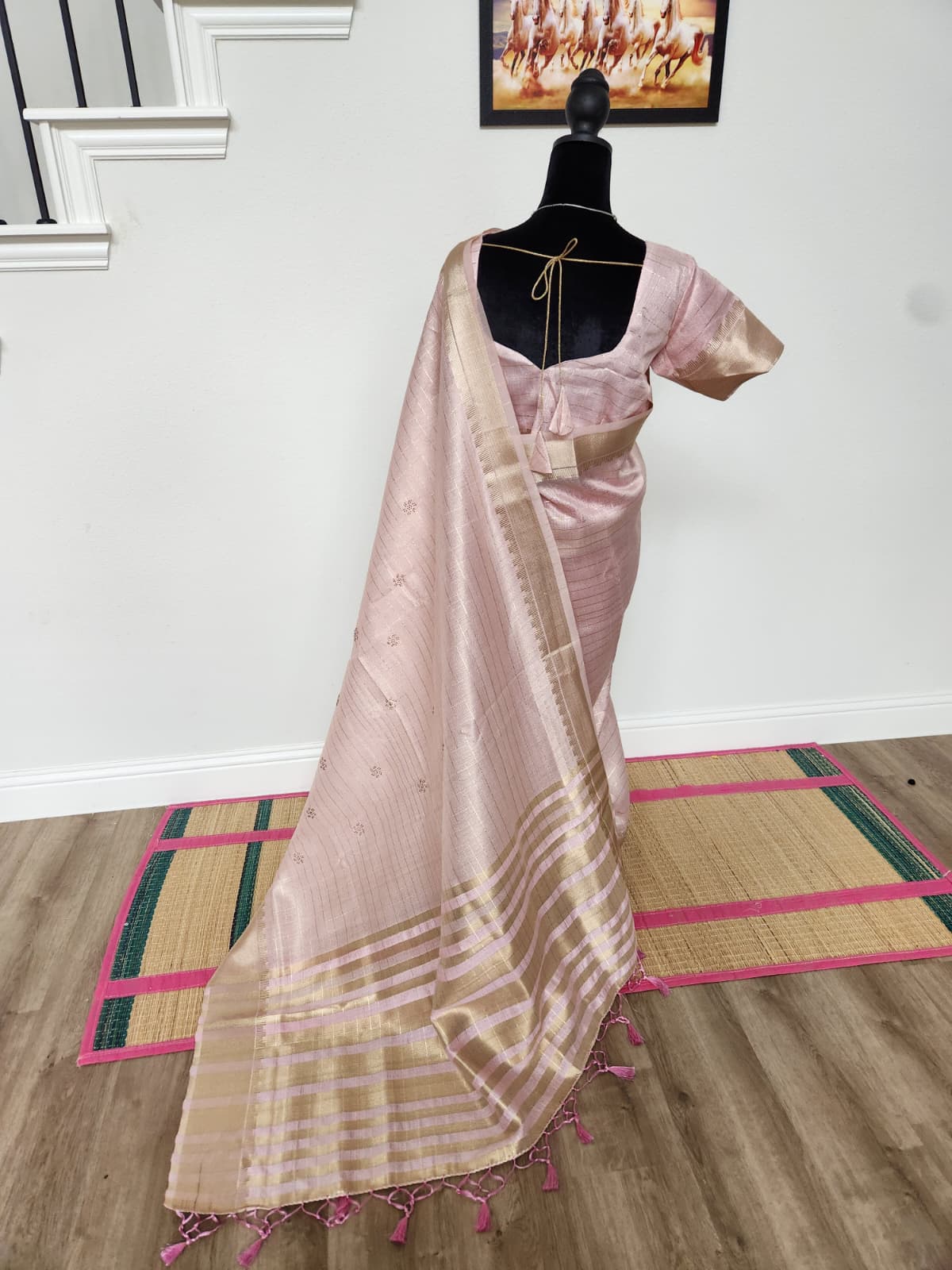 Natural-light back view of the baby pink saree with the pallu over the shoulder, zari buttis, gold stripes and pink tassels