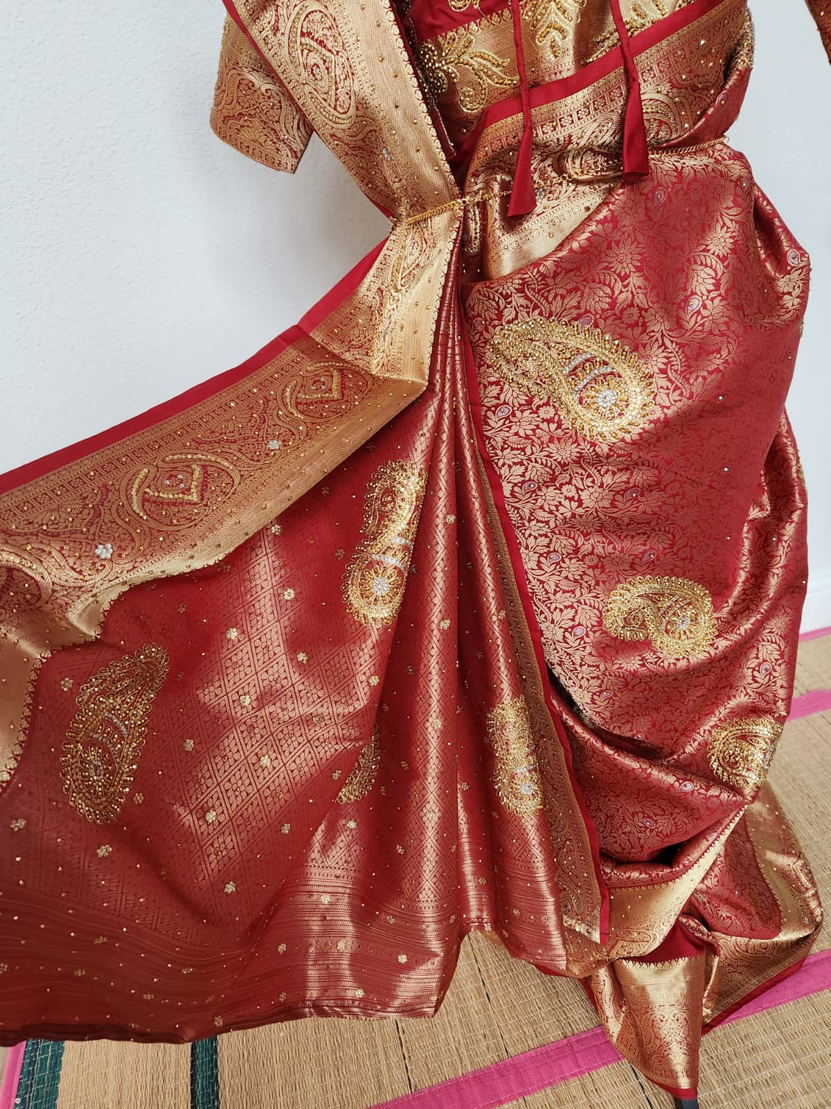 Natural-light close-up of the pleats showing the gold zardosi paisley work on red semi silk