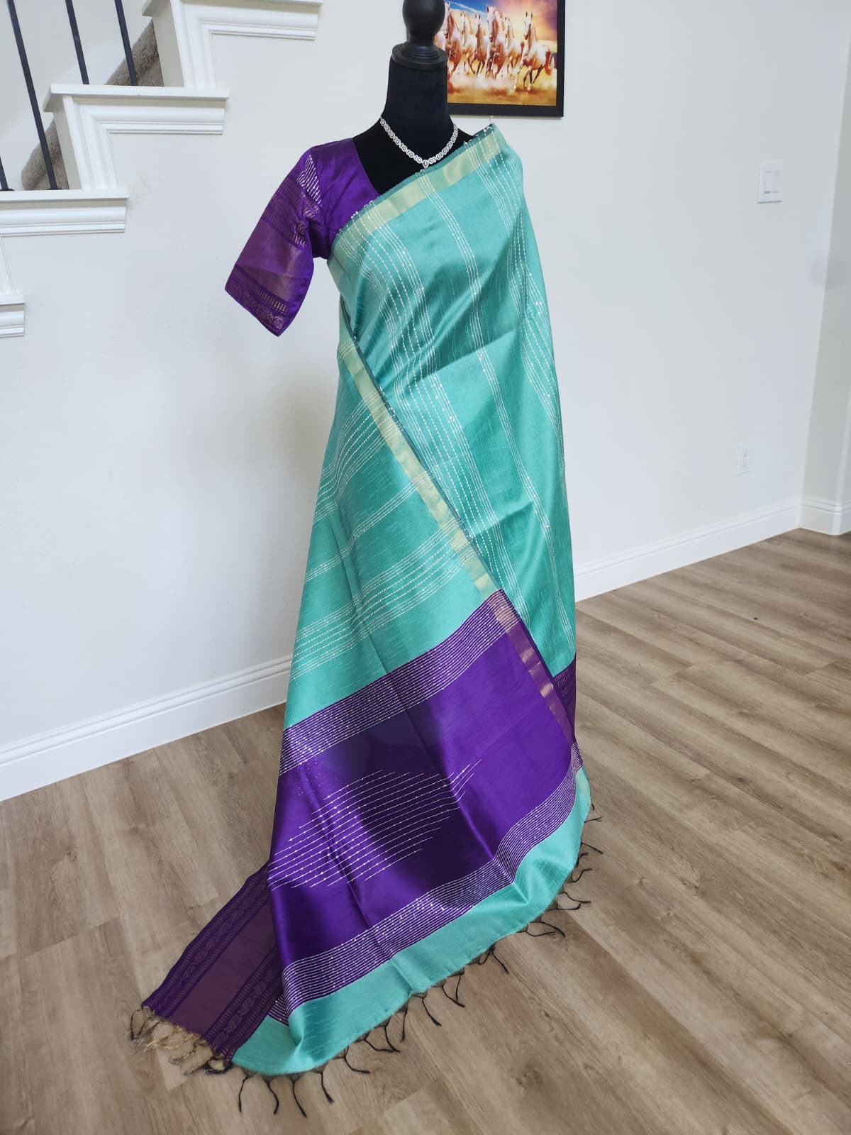 Natural-light front view of the turquoise saree with the royal purple pallu and fringe tassels