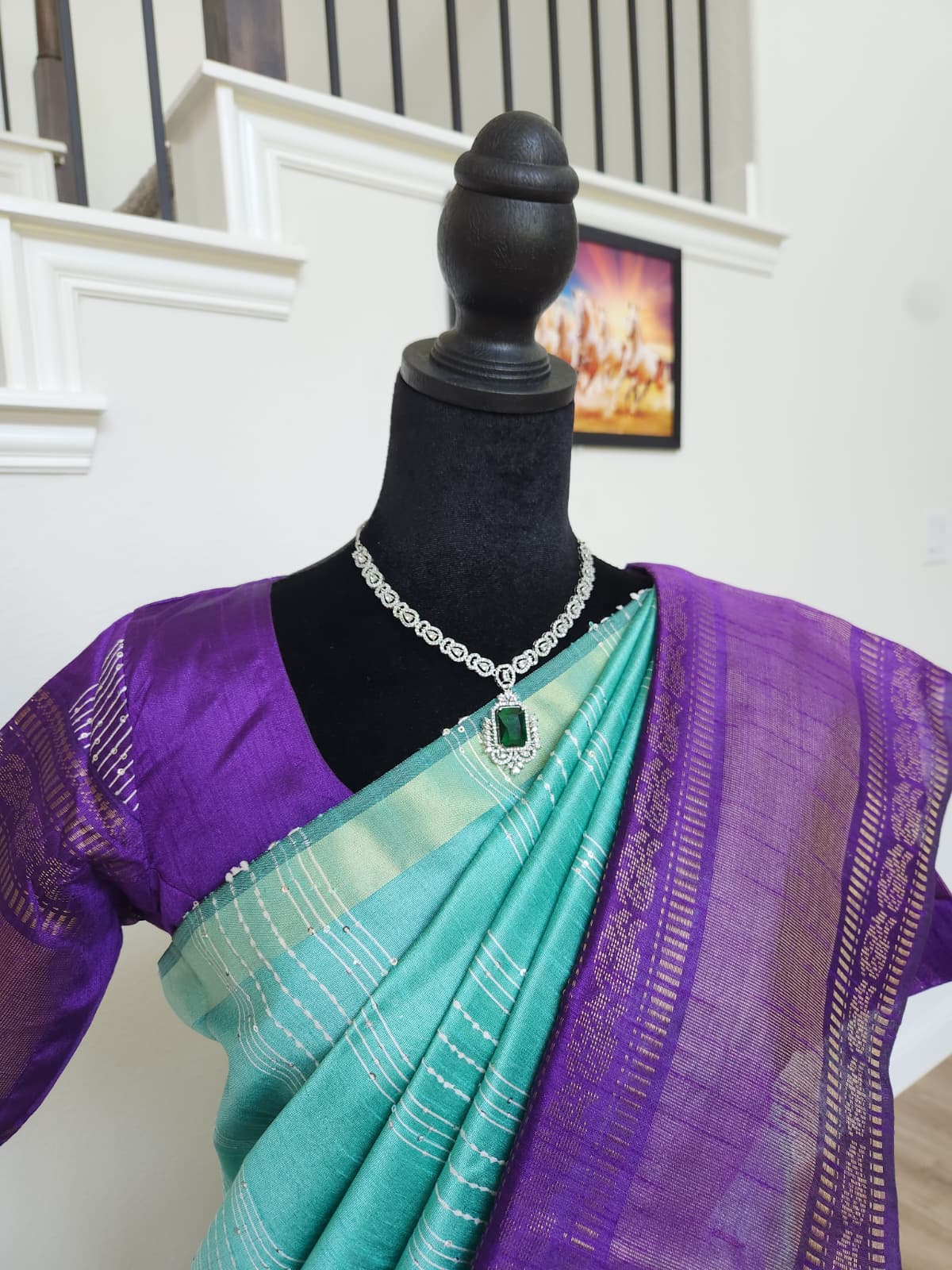 Natural-light close-up of the turquoise body, purple zari border and purple blouse