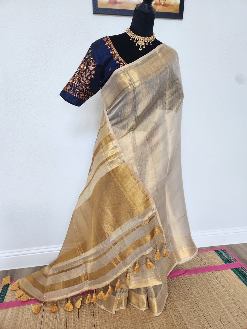 Natural-light photo of the golden Kadhi tissue silk saree, front view, showing its shimmer and tasseled pallu
