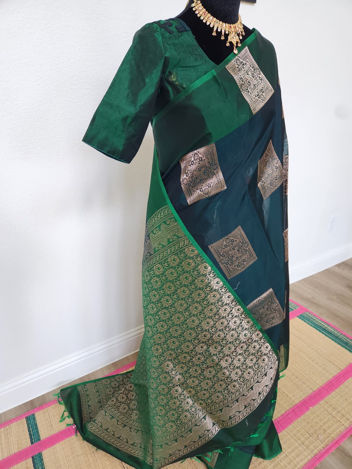 Natural-light close view of the bottle green saree drape showing the gold zari brocade pallu