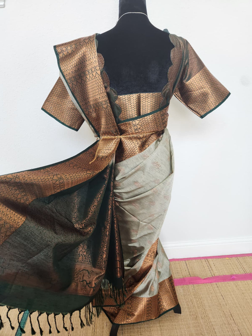 Natural-light back view of the copper pallu spread out with emerald green tassels