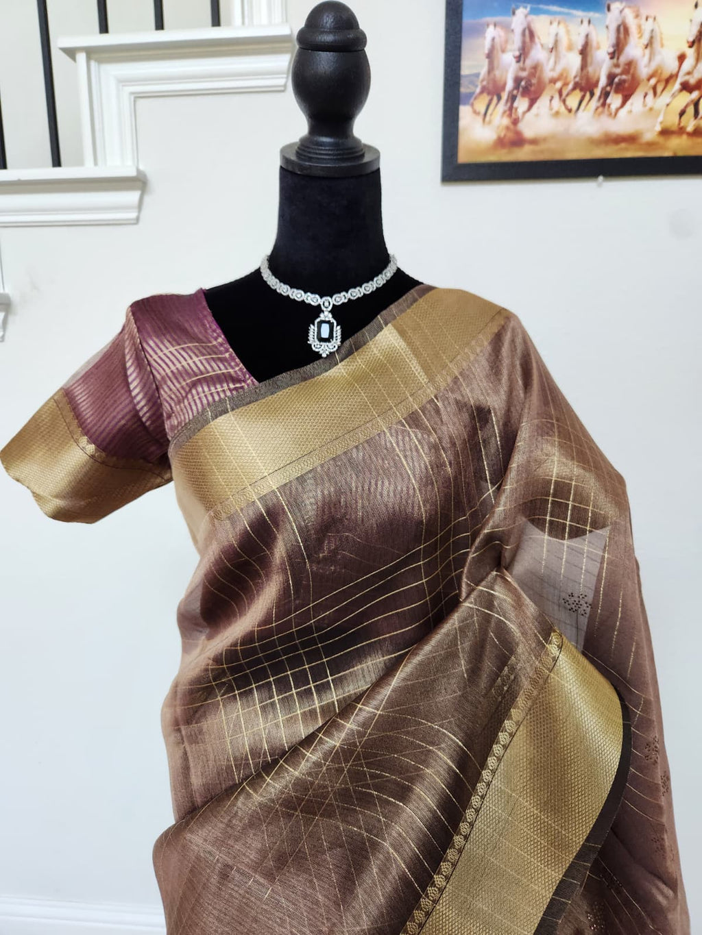 Natural-light close-up of the wine organza saree front with gold zari checks and border