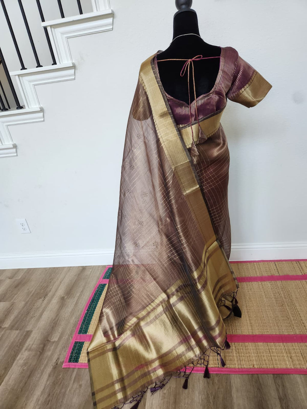 Natural-light side-back view of the wine organza saree showing the gold zari border on the pallu